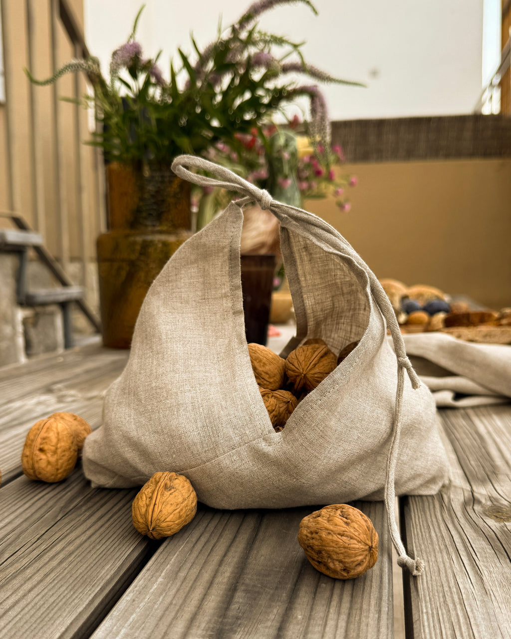 Natural linen bag with ties filled with walnuts on a wooden deck