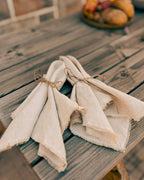 Two folded natural linen napkins tied with twine, displayed on a rustic wooden table.