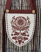 Linen belt bag with chocolate embroidery hanging on a reed fence