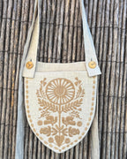 Linen belt bag with sand embroidery hanging on a reed fence