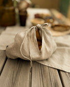 Linen bread bag holding a loaf of bread on a rustic wooden table