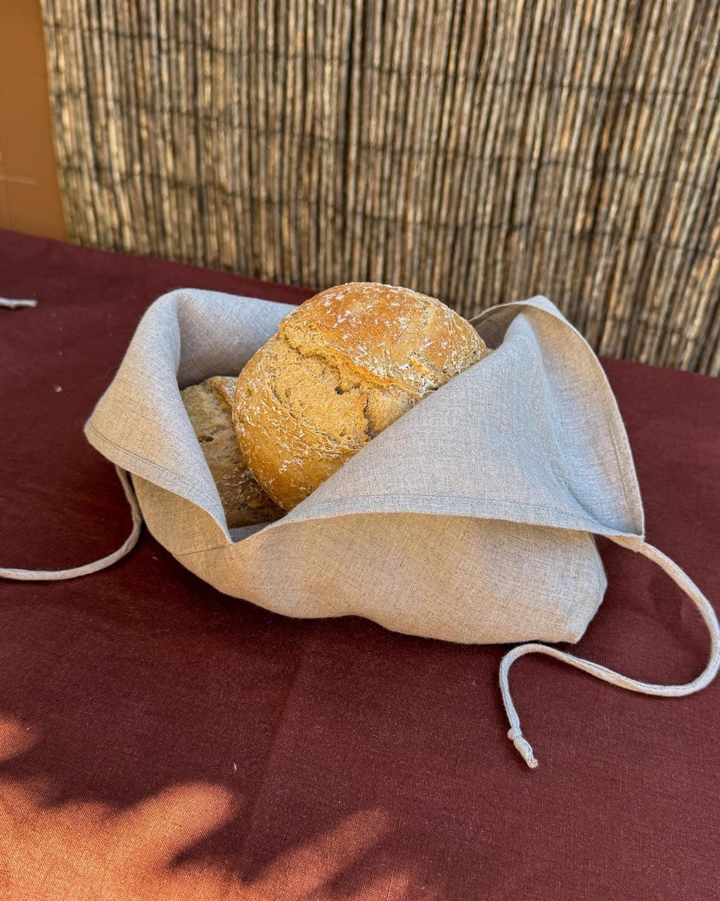 Linen bread bag opened flat with a round loaf inside