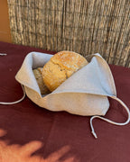 Linen bread bag opened flat with a round loaf inside